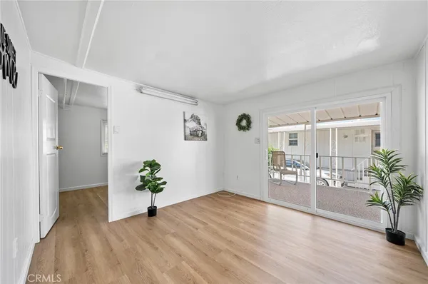 a view of an empty room with wooden floor and a potted plant