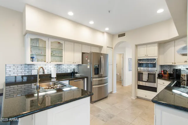 a kitchen with stainless steel appliances kitchen island granite countertop a stove refrigerator and cabinets