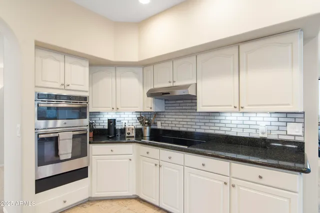 a kitchen with granite countertop white cabinets and white appliances