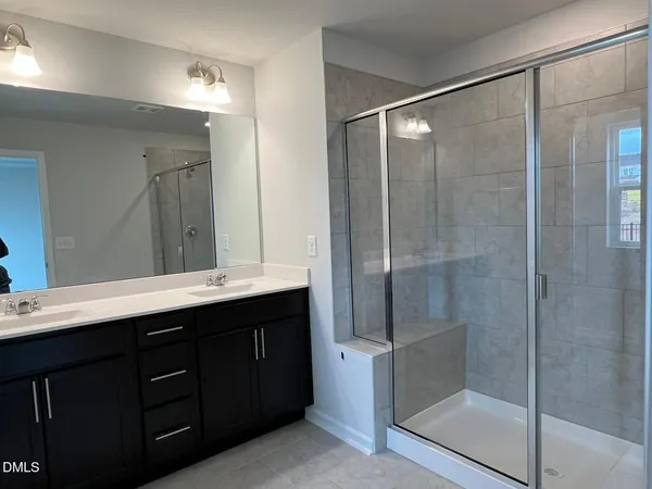 a bathroom with a double vanity sink mirror and shower