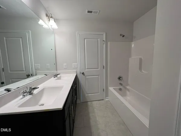 a bathroom with a double vanity sink a mirror and a bathtub