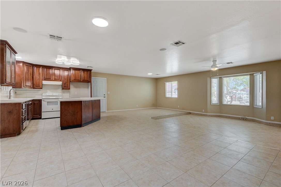 7631 Bermuda Road Las Vegas, NV 89123 - Photo 17 of 64 A combined kitchen and living area featuring warm wood cabinetry, a practical island, and ceramic tile flooring.
