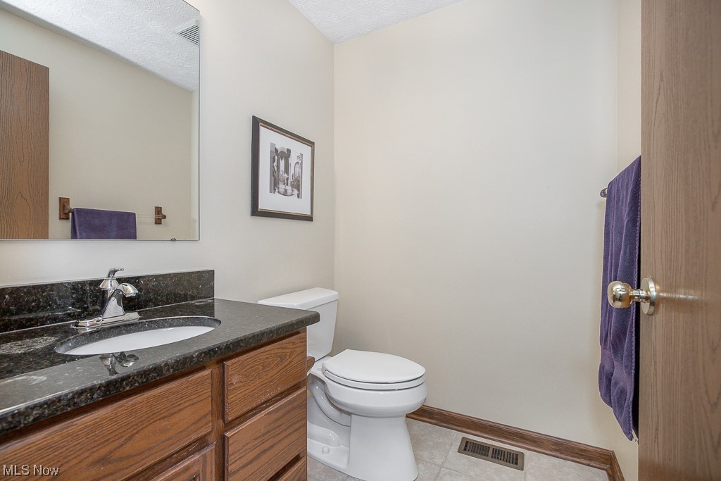 9708 Reed Road Grafton, OH 44044 - Photo 14 of 35 Bathroom with toilet, tile floors, a textured ceiling, and vanity