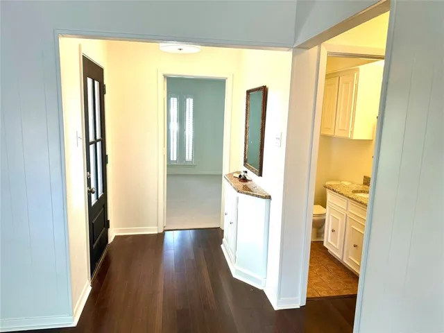 a view of a hallway with wooden floor and a living room