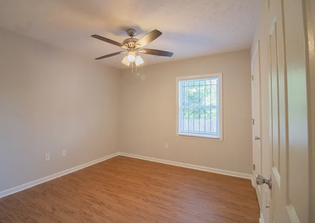 a view of an empty room with wooden floor and a window