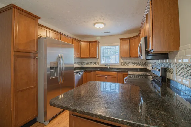 a kitchen with stainless steel appliances granite countertop a refrigerator a stove and a sink
