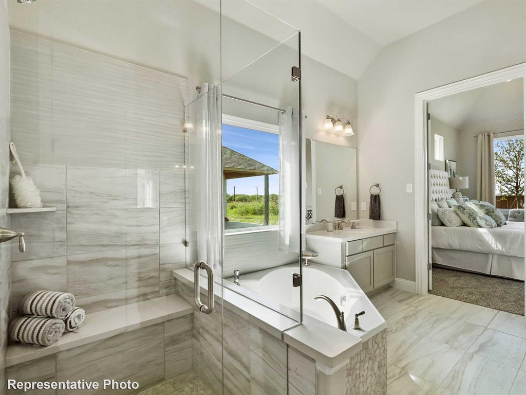 1143 Rothland Lane Red Oak, TX 75154 - Photo 10 of 18 Bathroom featuring a built-in soaking tub, a frameless glass shower enclosure with a built-in bench, a dual vanity with a built-in mirror, and light-toned tile flooring