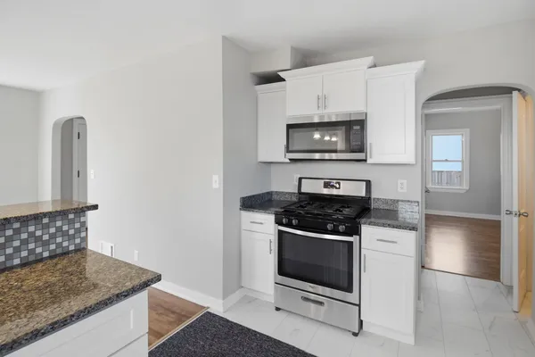 a kitchen with granite countertop white cabinets and stainless steel appliances