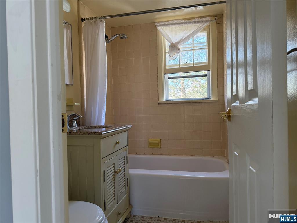 39 Franklin Street, Unit 2 Tenafly, NJ 07670 - Photo 11 of 27 a bathroom with a granite countertop sink toilet a mirror and a bathtub