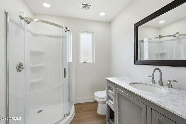 a bathroom with a granite countertop sink a toilet and shower