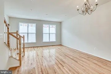 a view of an empty room with wooden floor and window