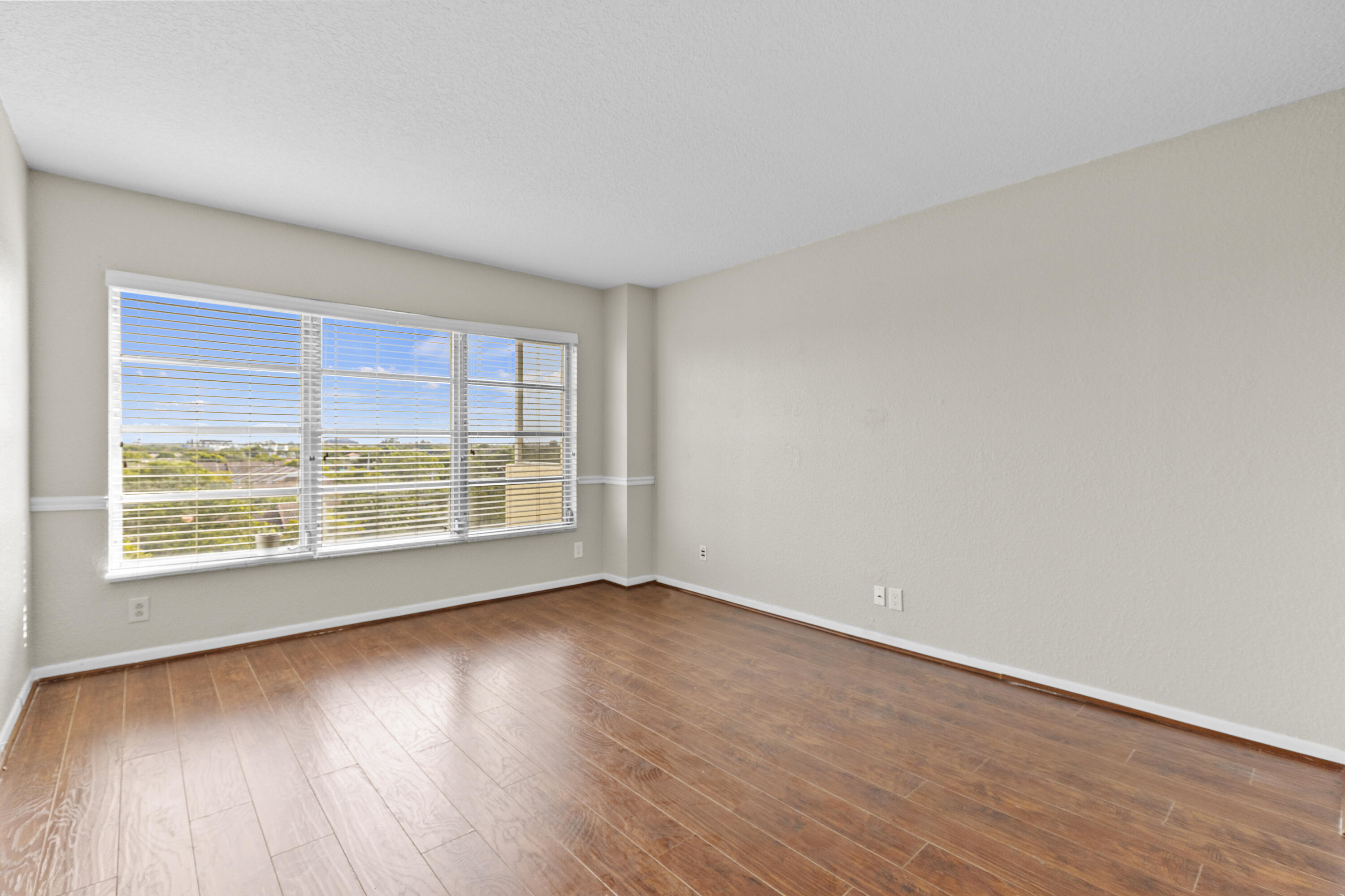 10777 West Sample Road, Unit 719 Coral Springs, FL 33065 - Photo 16 of 44 a view of an empty room with wooden floor and a window