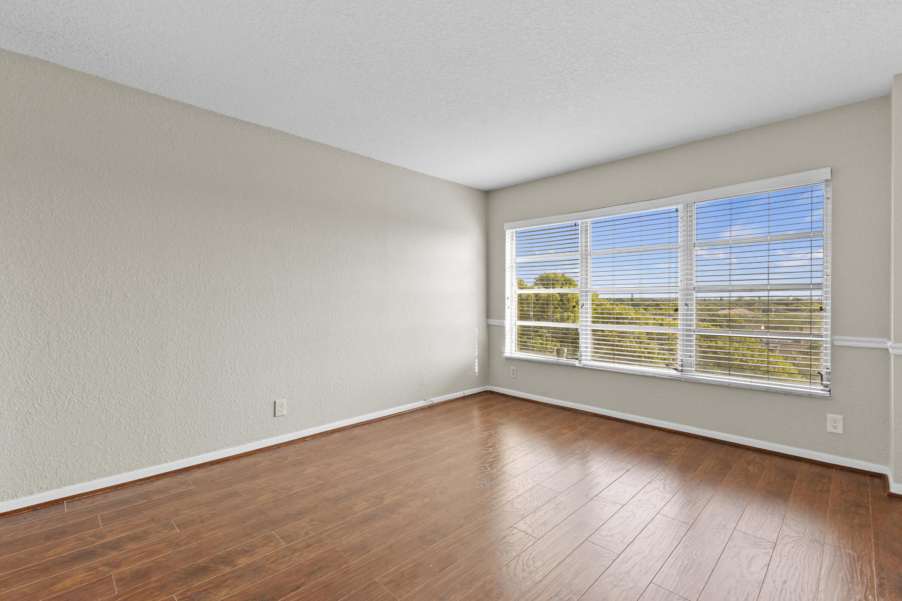 10777 West Sample Road, Unit 719 Coral Springs, FL 33065 - Photo 18 of 44 a view of an empty room with wooden floor and a window