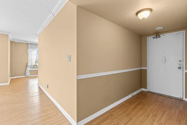 a view of an empty room with wooden floor and a window