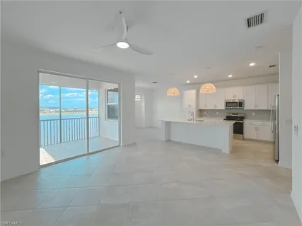 a large kitchen with kitchen island granite countertop a sink a stove a cabinets and a window