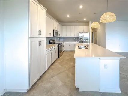 a large kitchen with kitchen island granite countertop lots of white cabinets and stainless steel appliances