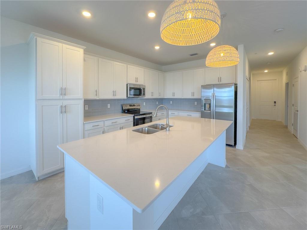 5583 Double Eagle Circle, Unit 4141 Ave Maria, FL 34142 - Photo 8 of 50 a large kitchen with stainless steel appliances a large counter top a stove a sink a refrigerator and a cabinets