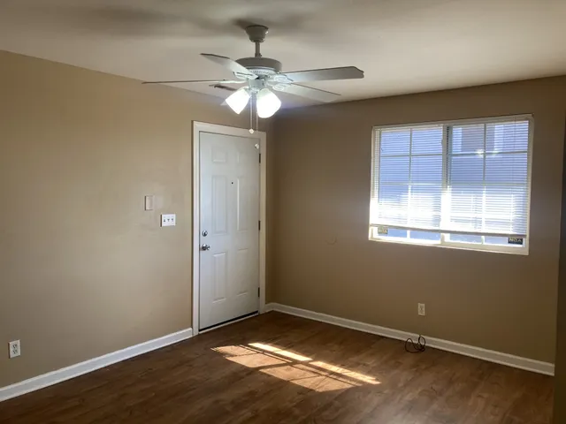 an empty room with wooden floor and windows
