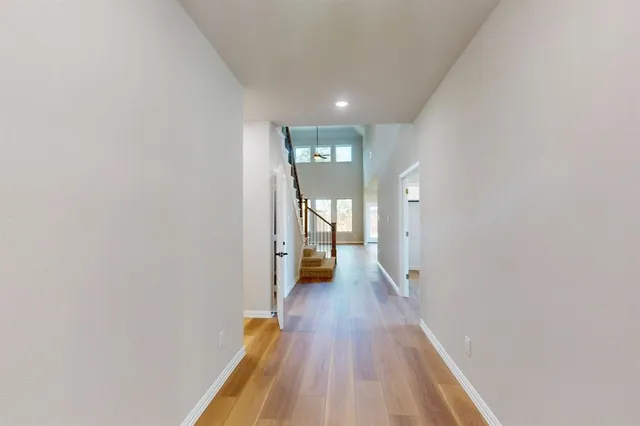 a view of a hallway with wooden floor and a bathroom