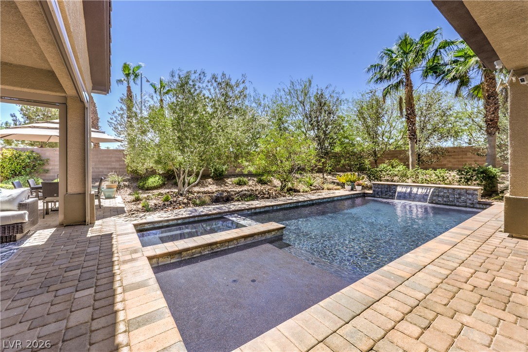 7119 Arabian Ridge Street Las Vegas, NV 89131 - Photo 49 of 73 Lush landscaping and a serene pool with a waterfall feature create a private outdoor oasis.
