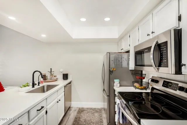 a kitchen with stainless steel appliances a sink a stove a microwave a refrigerator and cabinets