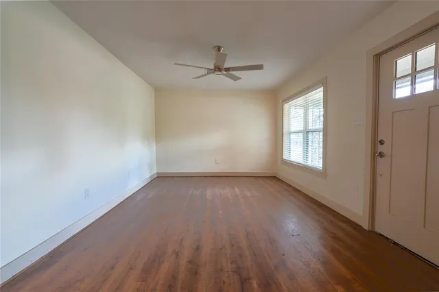 an empty room with wooden floor windows and ceiling fan