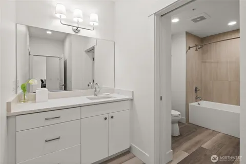 a bathroom with a double vanity sink a toilet and shower