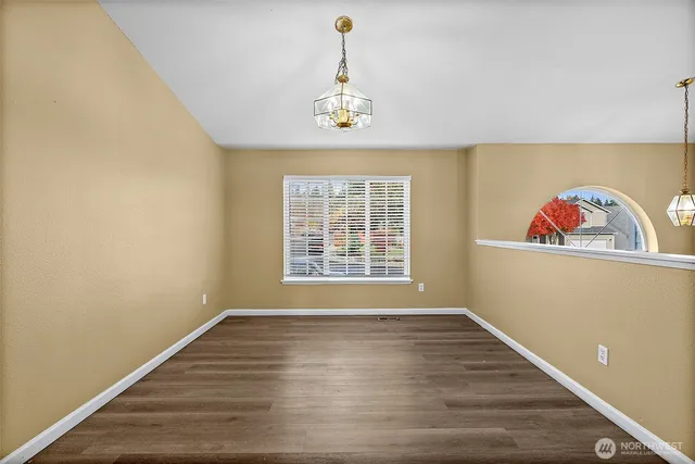 a view of an empty room with window and wooden floor