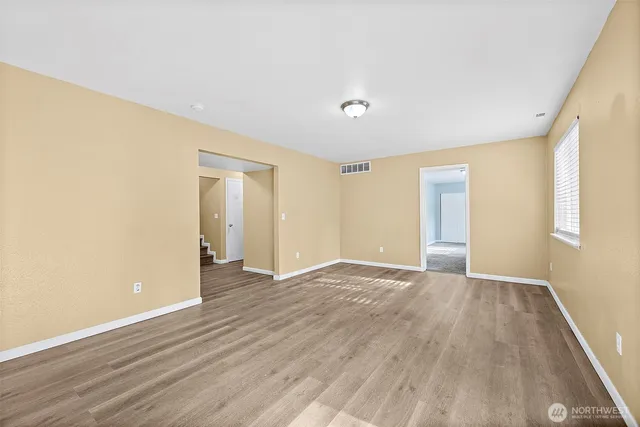 a view of an empty room with wooden floor and a window