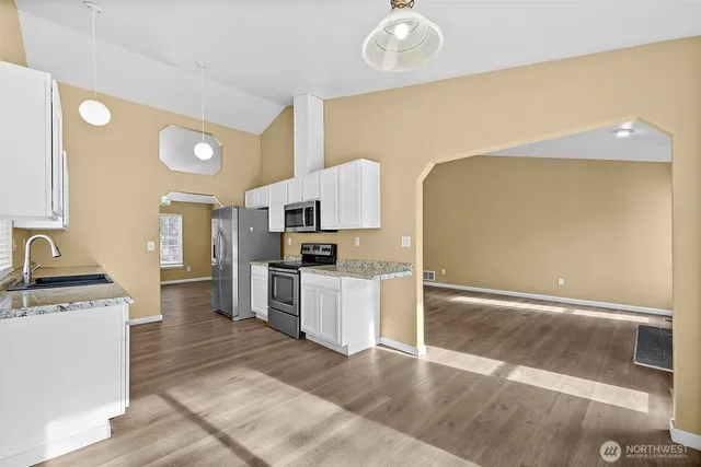 a kitchen with granite countertop stainless steel appliances a stove sink and microwave