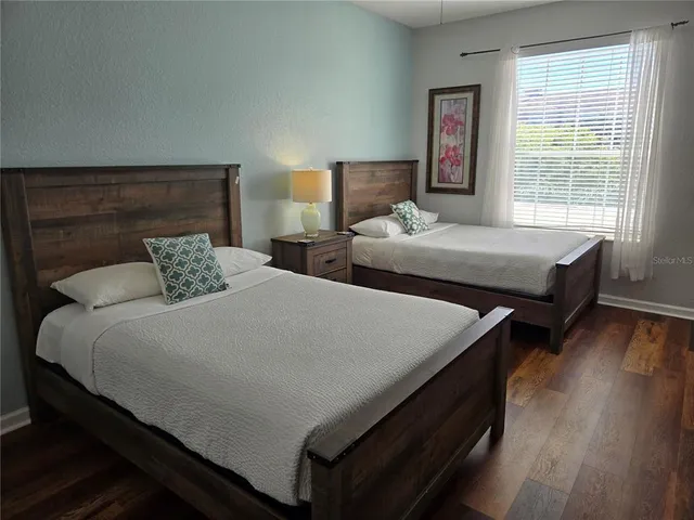 a bedroom with two beds and wooden floor