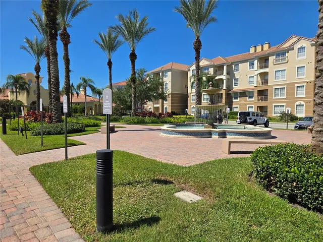 a front view of a building with garden and trees