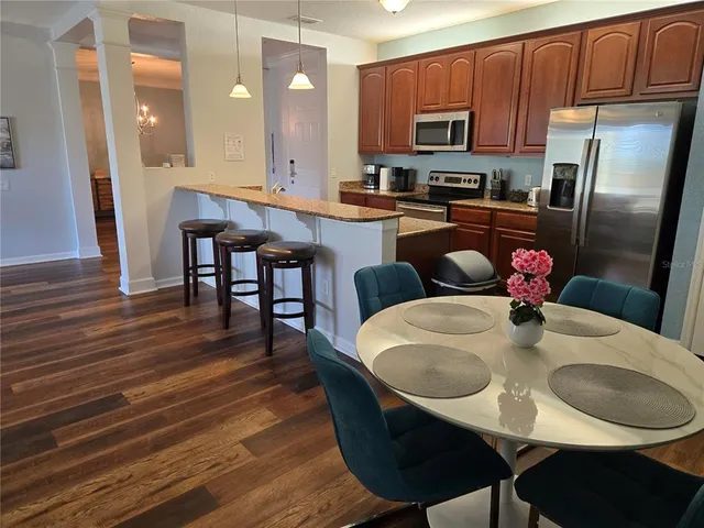 a kitchen with stainless steel appliances granite countertop a kitchen island a stove a table and a refrigerator