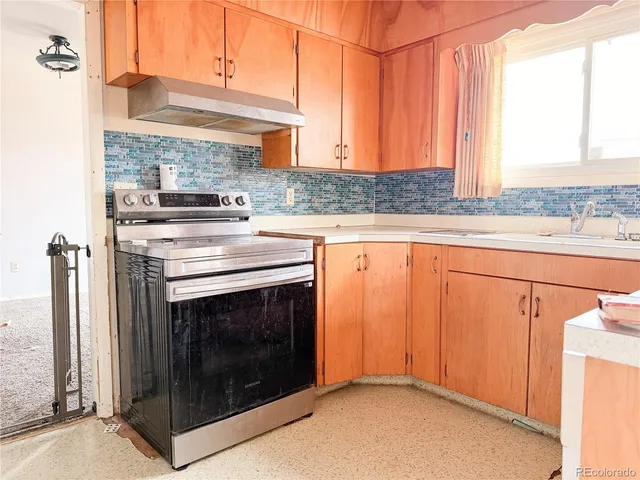 a kitchen with granite countertop a sink a stove and cabinets