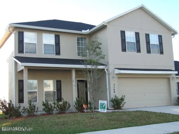 a front view of a house with a yard and plants