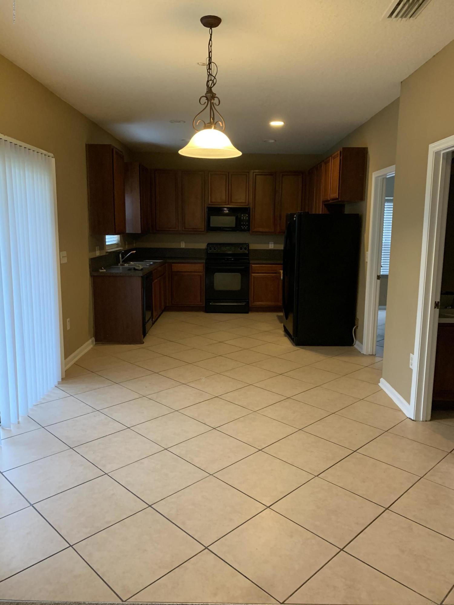 7140 Rampart Ridge Circle West Jacksonville, FL 32244 - Photo 11 of 13 a kitchen with stainless steel appliances kitchen island granite countertop a refrigerator and a stove top oven