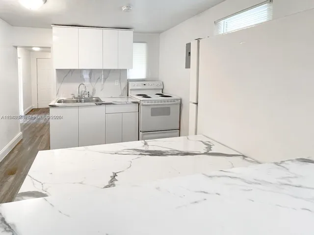 a kitchen with granite countertop a sink cabinets and stainless steel appliances