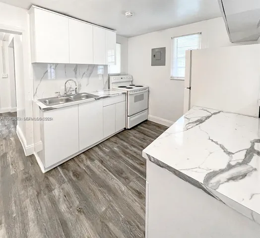 a kitchen with a sink a stove and white cabinets