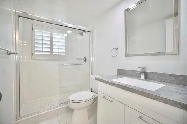 a bathroom with a granite countertop sink a toilet and shower