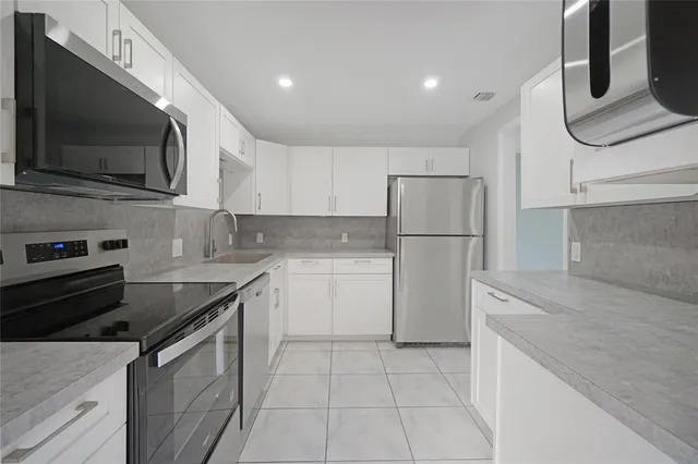 a kitchen with a sink a microwave a refrigerator and cabinets