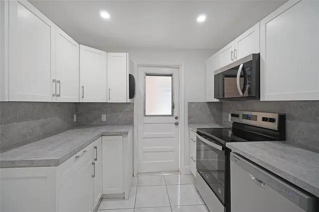 a kitchen with granite countertop white cabinets stainless steel appliances and a sink