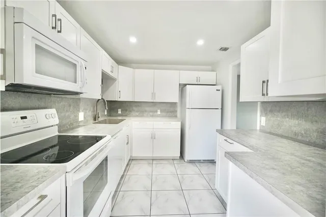 a kitchen with a sink a refrigerator and cabinets