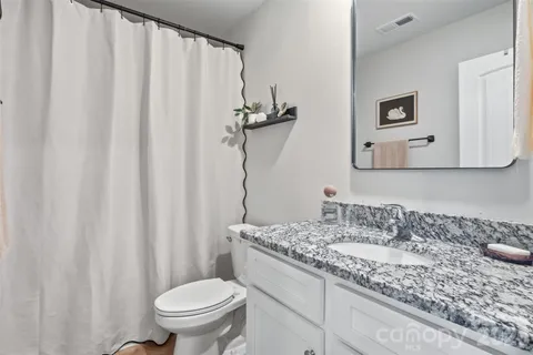 a bathroom with a granite countertop sink and a toilet
