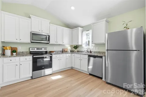 a kitchen with granite countertop white cabinets and stainless steel appliances