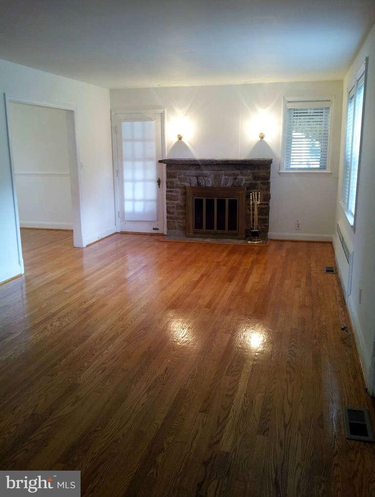 8412 Old Harford Road Baltimore, MD 21234 - Photo 2 of 25 an empty room with wooden floor fireplace and windows