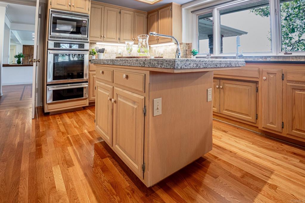 145 Yucca Road Fallbrook, CA 92028 - Photo 16 of 58 a kitchen with granite countertop wooden floors and stainless steel appliances