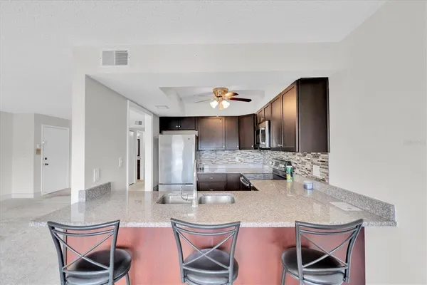 a view of kitchen with kitchen island stainless steel appliances refrigerator stove dining table and chairs