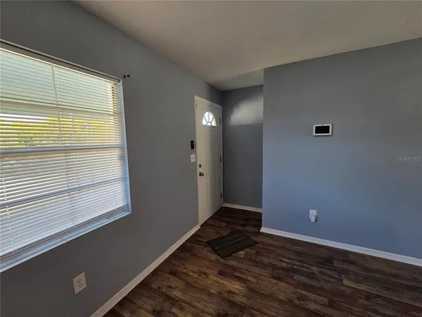 a view of an empty room with wooden floor and a window