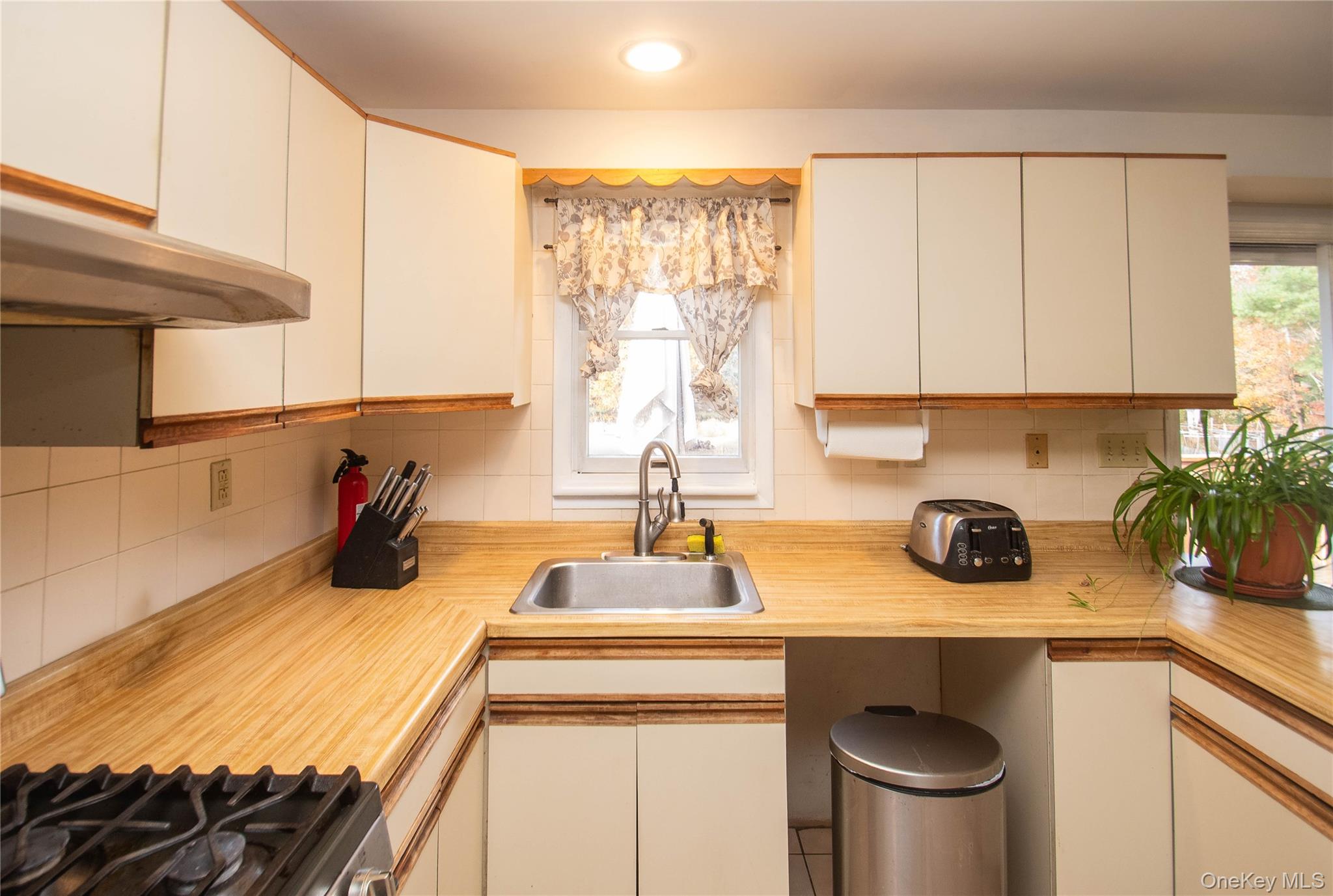 20 Valley Road Forestburgh, NY 12777 - Photo 12 of 38 Kitchen featuring light countertops, backsplash, under cabinet range hood, gas range, and healthy amount of natural light
