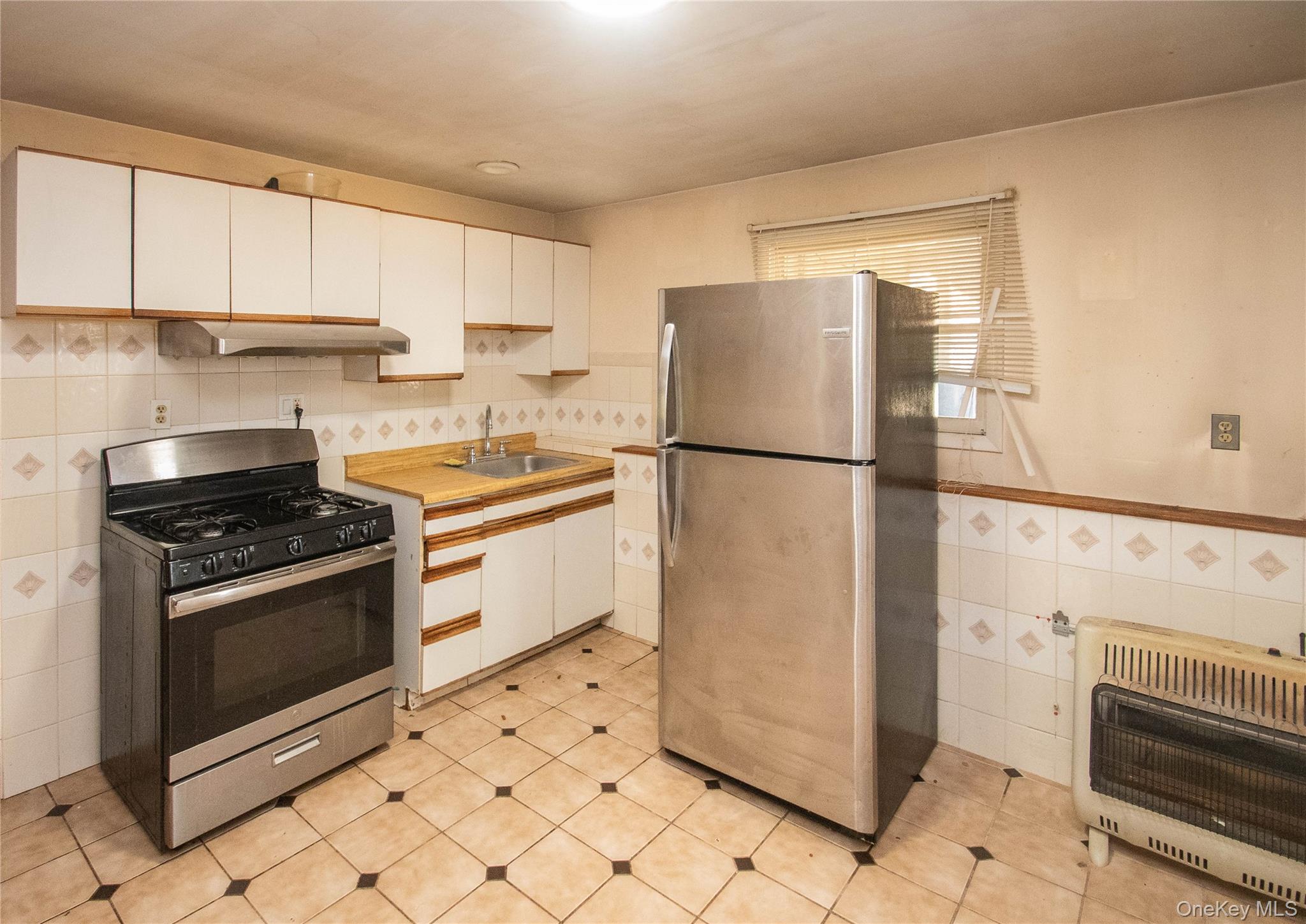 20 Valley Road Forestburgh, NY 12777 - Photo 26 of 38 Kitchen with stainless steel appliances, white cabinetry, tile walls, heating unit, and light countertops
